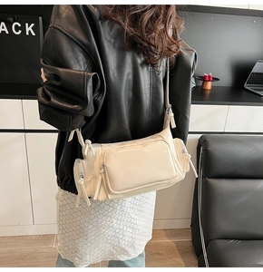 Detail view of cream white multi-pocket PU crossbody bag with knotted zip pulls