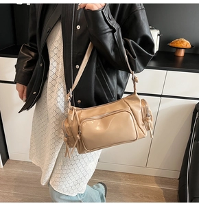 Detail of beige patent leather bag with silver zippers and adjustable crossbody strap
