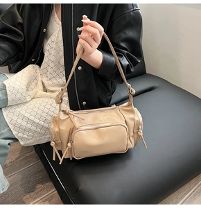 Detailed view of beige glossy faux leather shoulder bag with multiple zipper pockets