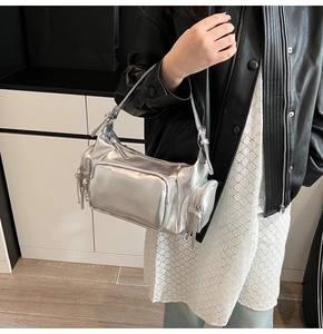 Detail of silver metallic Y2K shoulder bag featuring multiple zipper pockets and tassels