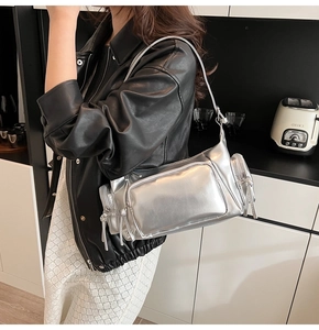 Detail of silver metallic motorcycle bag with multi-pocket design and zippers on shoulder