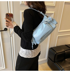 Close-up of light blue patent leather shoulder bag with zipper details and glossy finish
