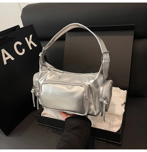Detail of silver metallic handbag with multiple zipper pockets on premium gift box packaging