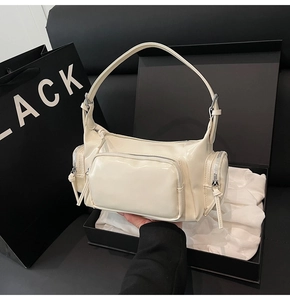 Detail of a creamy white vintage biker shoulder bag with glossy finish and pockets