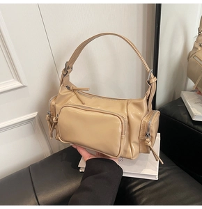 Detailed close-up of beige patent leather bag with multiple zippers and silver hardware