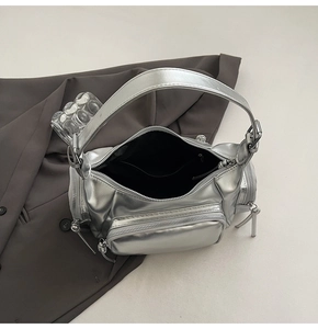Close-up of metallic silver motorcycle bag with multiple zippers on grey blazer