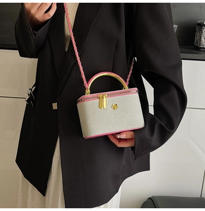 Detail of a mini grey crossbody bag with pink trim and gold handle shown on a model