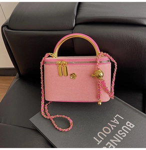 Detailed view of a pink quilted mini vanity bag with a gold flower logo and metal handle