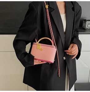 Detail of pink quilted crossbody bag with golden handle and chain strap on a model