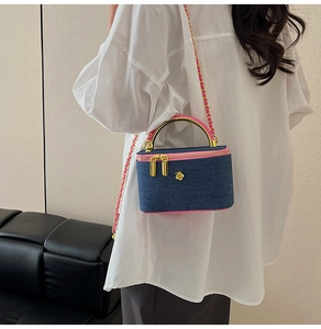 Quilted denim crossbody bag with pink trim and gold flower detail on white shirt
