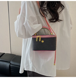 Detail of a chic chain strap vanity bag featuring pink trim and gold flower accent