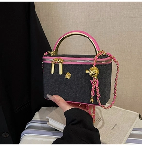 Detail of black quilted crossbody bag with pink trim, gold camellia and chain strap