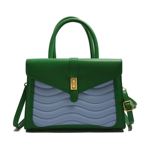 Green and purple wavy patchwork handbag with gold clasp and dual handles on white background