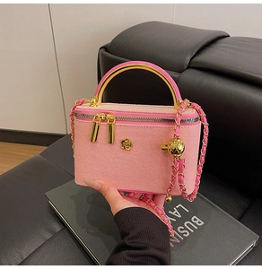 Detail of pink quilted box bag featuring camellia metal clasp and golden chain strap
