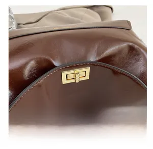 Detail of a dark brown oil wax leather tote with a gold metal twist lock and logo