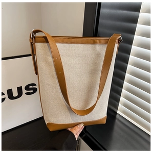 Detail of canvas bucket bag showing brown leather stitching and adjustable strap