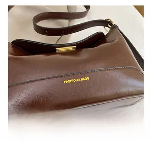 Macro detail of dark brown leather tote showing gold metal clasp and fashion engraving