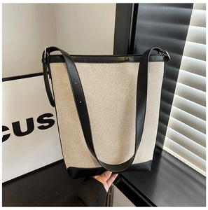 Close-up of stylish bucket tote bag showing cream canvas and black leather patchwork