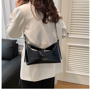 Detail of high-gloss black tote bag with gold lettering and metallic clasp closure