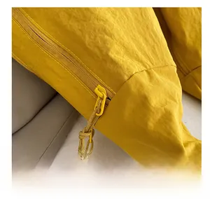 Detail showing bright yellow nylon fabric texture and smooth zipper with woven puller