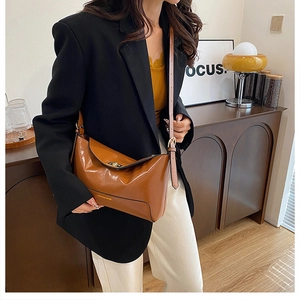 Detail view of brown glossy leather tote bag with metal twist lock and fashion logo