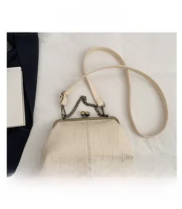 Detail of beige faux crocodile skin texture and vintage metal clasp on a shoulder bag