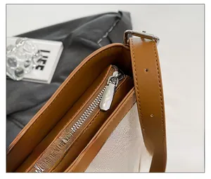 Detail view of the silver zipper and brown leather strap on the canvas bucket bag