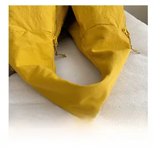 Detail of wide ginger yellow nylon shoulder strap with textured pleats on a tote bag