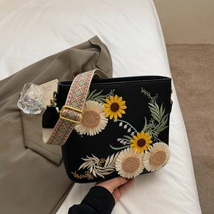 Minimalist black square crossbody bag with floral embroidery and woven strap