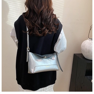 Modern silver rectangular crossbody bag with metallic finish shown on a model's shoulder