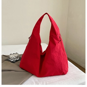 Detail of red nylon tote bag featuring wrinkled texture and side hidden zipper pocket