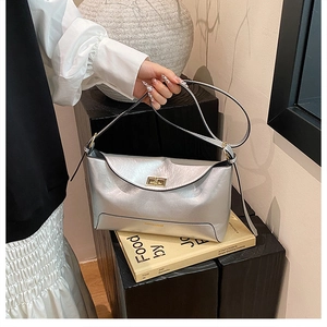 Detail view of silver metallic tote bag with gold buckle and fashion logo on book