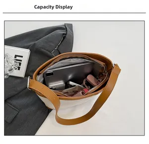 Interior view showing the large capacity of the beige canvas and brown leather bucket bag