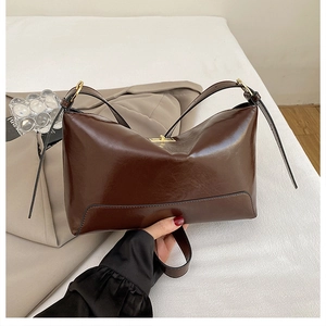 Detail of dark brown tote with glossy leather texture and elegant golden metal clasp