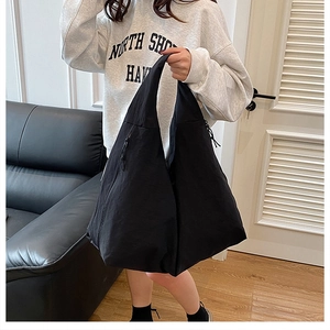Detail view of large black tote bag with drawstring accents on a model in a modern home