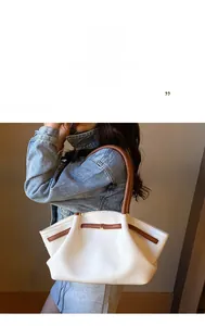 Detail der weißen Leder-Tote-Bag mit braunen Kontrastgriffen und goldenen Beschlägen