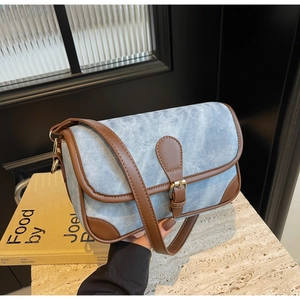 Close-up of retro denim handbag with brown leather straps and metallic buckle detail