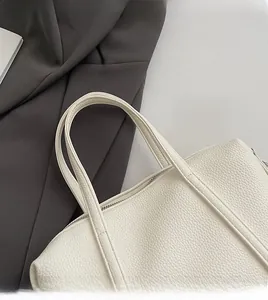 Close-up of litchi texture leather tote bag handle and precision stitching in cream white