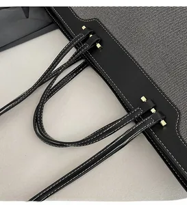 Close-up of contrasting grey canvas and black leather strap with gold hardware and stitching