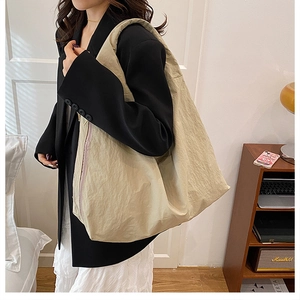 Detailed view of beige tote bag showing natural wrinkled nylon texture and wide shoulder strap