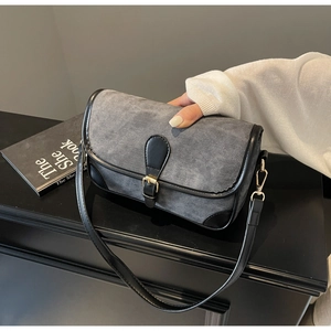 Detail of grey denim shoulder bag with black leather trim and golden buckle closure