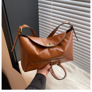 Detail of vintage brown leather tote bag featuring a golden twist-lock and fine grain texture
