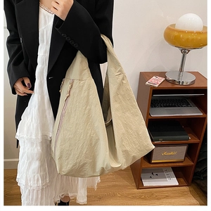 Detail of the minimalist beige oversized tote bag with wrinkled texture and wide strap