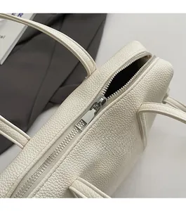 Detail shot of smooth silver metal zipper on white litchi textured leather handbag