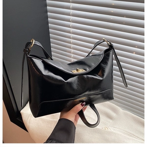 Detail shot of black faux leather tote bag with gold twist lock and brand lettering