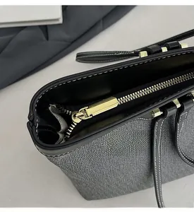 Macro detail of high-quality smooth gold zipper and black leather trim on grey textured bag