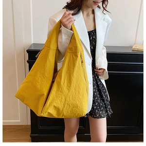 Detail view of a large yellow shoulder bag featuring soft textured nylon and zipper pull