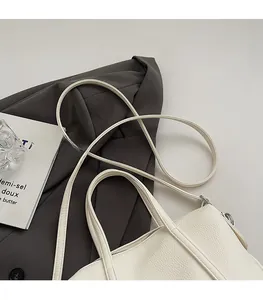 Close-up of cream leather tote bag featuring litchi texture and silver metal hardware