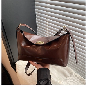 Detail of vintage brown leather tote bag with gold metal twist lock and embossed logo