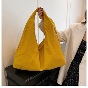 Detailed close-up of large yellow crinkled nylon tote bag with wide shoulder strap